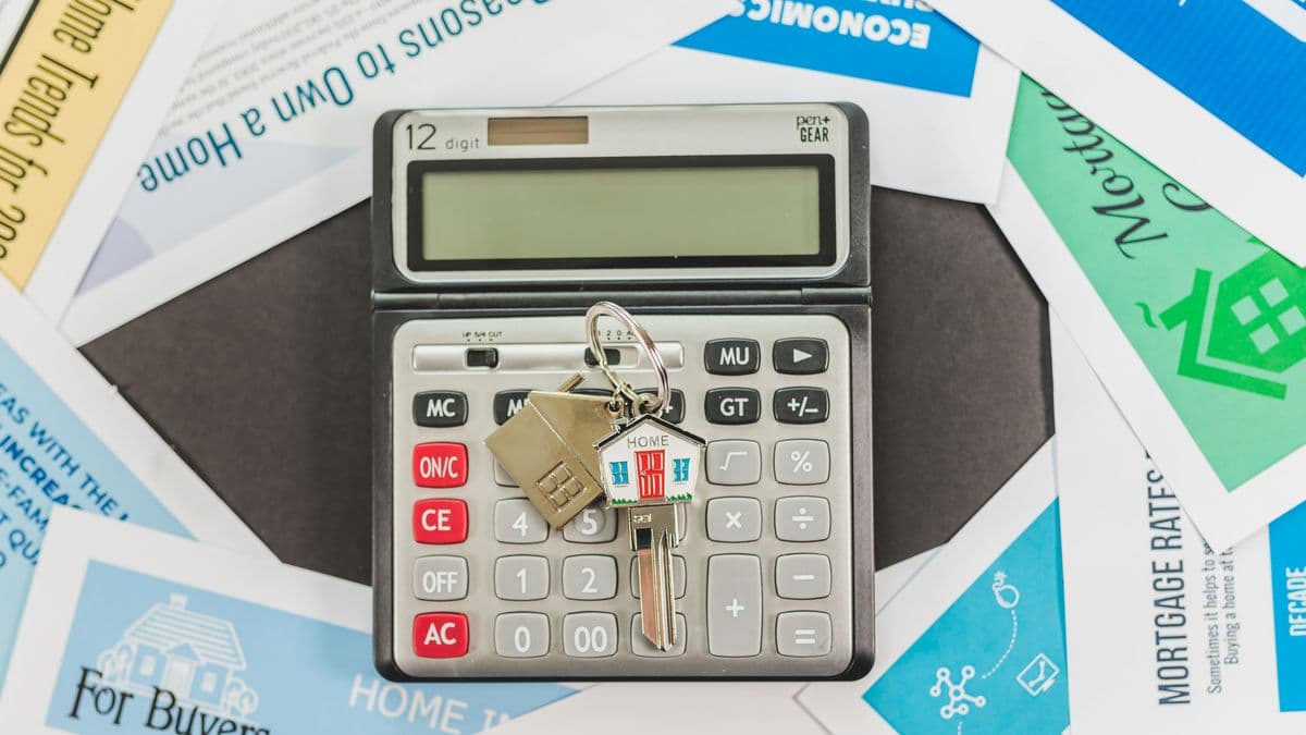 Pareja revisando documentos de un crédito hipotecario en una mesa con una maqueta de casa pequeña