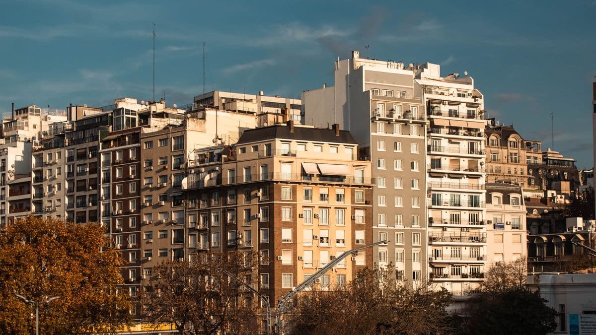 Plano de departamento sobre escritorio con calculadora y documentos inmobiliarios