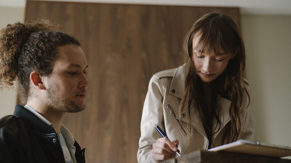 Una pareja revisa y firma los papeles de un alquiler