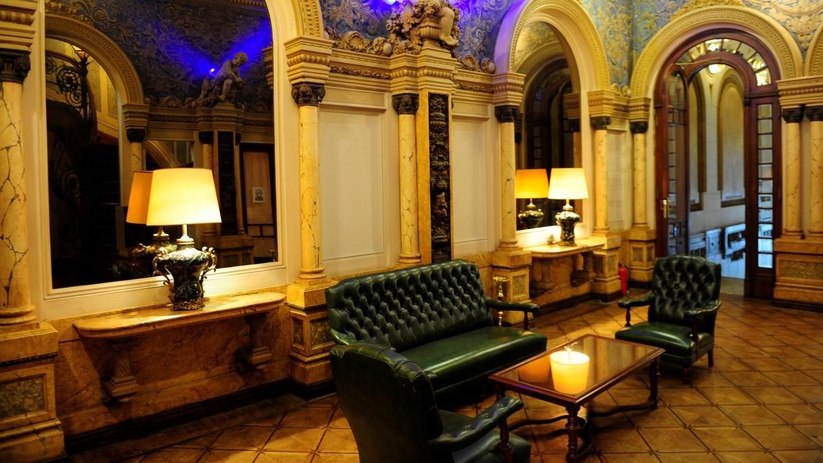 Los sillones de cuero verde y las lámparas de mesa conviven con espejos, molduras y revestimientos trabajados en uno de los salones del antiguo palacio (Foto: Adrián Cavalheiro)