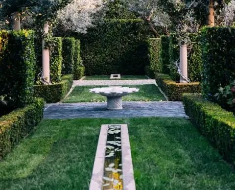 Jardines de la mansión en Beverly Hills: El diseño paisajístico incorporó senderos, setos recortados, una fuente central y espacios verdes que refuerzan el estilo clásico de la propiedad