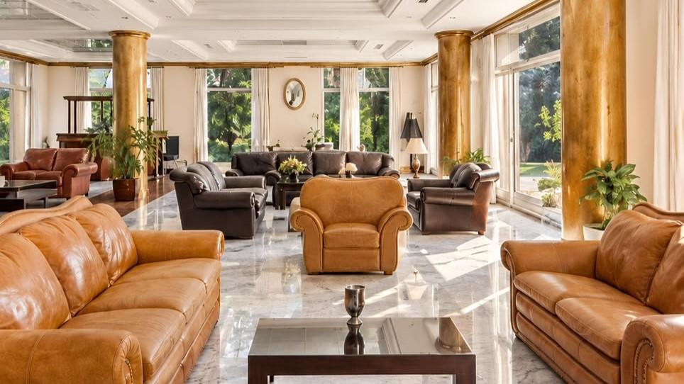 El living principal se destaca por sus amplios ventanales, columnas revestidas y conexión directa con el parque de la propiedad